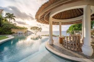 a pool at a resort with the ocean in the background at Villa Nirvana Biru Bingin Beach in Uluwatu
