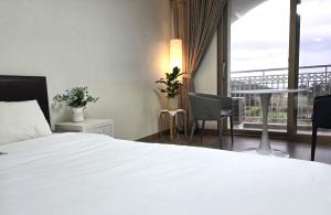 a bedroom with a white bed and a balcony at MJ Pension & Resort in Seogwipo