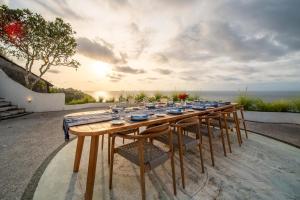 a long wooden table with chairs and the ocean at Villa Nirvana Biru Bingin Beach in Uluwatu
