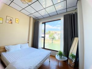 een slaapkamer met een bed en een groot raam bij DH Homestay Cao Bằng in Cao Bằng