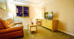 a hotel room with a couch and a television at Sacheon Tourist Hotel in Sacheon