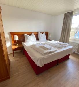 um quarto com uma cama com lençóis brancos e almofadas em Hotel Vienenburg em Goslar
