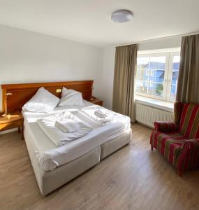 um quarto com uma cama branca e uma cadeira vermelha em Hotel Vienenburg em Goslar
