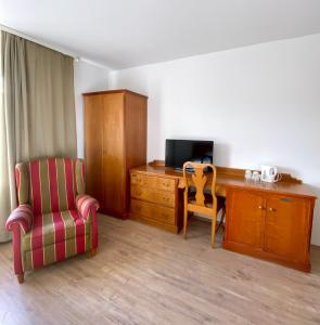 um quarto com uma secretária, uma cadeira e uma secretária com uma televisão em Hotel Vienenburg em Goslar