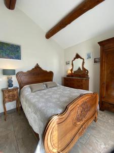 a bedroom with a large wooden bed and wooden furniture at La Petite Garrigue in Mérindol