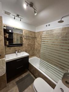 a bathroom with a tub and a sink and a toilet at Apartamento en casco Histórico. in San Lorenzo de El Escorial