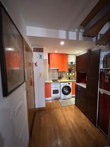 cocina con armarios naranjas y nevera blanca en Apartamento en casco Histórico., en San Lorenzo de El Escorial