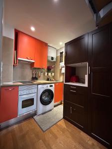 a kitchen with orange cabinets and a washing machine at Apartamento en casco Histórico. in San Lorenzo de El Escorial