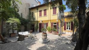 a courtyard with a yellow house with red shutters at Chez papa in Ravenna