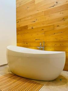 y baño con bañera blanca y paredes de madera. en Maison de rêve avec piscine à 5 minutes du lac., en Portalban- Dessous