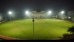 un campo de béisbol iluminado por la noche con luces en The Daman Club en Damān