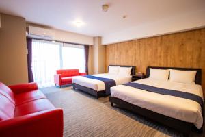 ein Hotelzimmer mit 2 Betten und einem roten Sofa in der Unterkunft Hotel Fu-Rin in Fukuoka