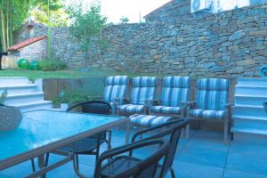 a patio with chairs and tables and a stone wall at 205 Dekani in Dekani