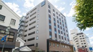 un edificio blanco alto con un letrero. en Iroha Grand Hotel Matsumoto Eki-Mae, en Matsumoto
