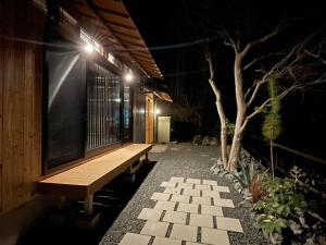 um alpendre com um banco e uma árvore à noite em 由良民泊島宿 em Matsuyama