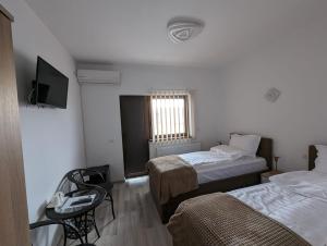 a room with two beds and a chair and a television at 2Family in Focşani