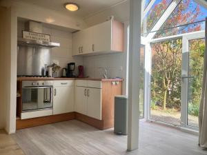 a kitchen with white cabinets and a large window at Dijkrose in Oostmahorn