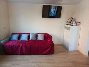 ein Schlafzimmer mit einem roten Bett mit drei Kissen in der Unterkunft Parko apartamentai Self check in in Klaipėda