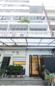 Theme Stories - Boutique Guesthouse في بانكوك: مبنى ابيض نوافذه ونباتاته امامه