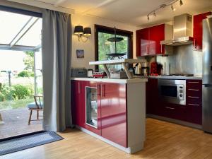 uma cozinha com armários vermelhos e uma grande janela em 4 pers Holiday Home Hilla with winter garden in front of the dike directly on the Lauwersmeer em Anjum