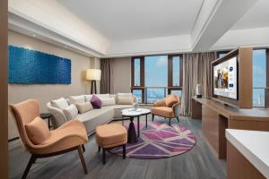 a living room with a couch and chairs and a tv at Hampton by Hilton Guangzhou Luoxi in Guangzhou