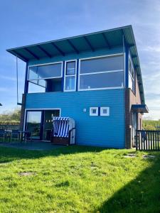 una casa azul con dos bancos delante en 6pers. Lauwersmeer Lakefront. Nirvana house with sauna, pellet stove, en Anjum