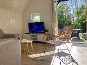 ein Wohnzimmer mit einem TV und einem Stuhl in der Unterkunft Grachthaus 6pers House with a private terrace and garden by the Lauwersmeer in Anjum