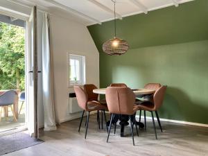 ein Esszimmer mit grünen Wänden sowie einem Tisch und Stühlen in der Unterkunft Olivia 6pers House with a private garden close to the National Park Lauwersmeer in Anjum