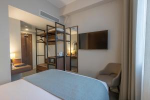 a bedroom with a bed and a chair and a television at Riu Plaza The Gresham Dublin in Dublin
