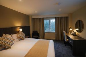 EcclestonにあるPark Hall Hotel,Chorley,Prestonのベッド、デスク、窓が備わるホテルルームです。