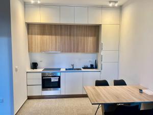 cocina con armarios blancos y mesa de madera en Diamant apartment pri sejmu MOS, en Celje