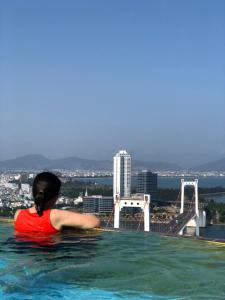 a woman in a swimming pool with a view of a bridge at Luxury Ocean View Danang Golden Bay in Da Nang