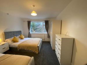 a bedroom with two beds and a dresser and a window at Spacious 4BR Home Near The NEC The Airport and Heartlands Hospital in Birmingham