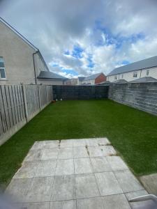 a large backyard with a brick wall and grass at Extra large Room in new house at Citywest in Dublin