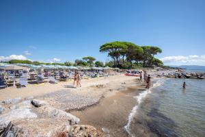 un gruppo di persone su una spiaggia con sedie e ombrelloni di Villaggio Il Girasole a Follonica