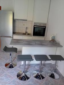 a kitchen with three bar stools in front of a counter at Apartment Novaković in Mirce
