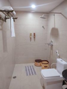 a white bathroom with a shower and a toilet at Hotel Hindustan Inn in Kuchaiburi