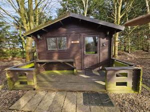 a small wooden cabin with a porch in the woods at Willow by Paymán Club in Royston