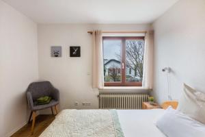 ein Schlafzimmer mit einem Bett, einem Fenster und einem Stuhl in der Unterkunft Ferienwohnung Schwarzwaldblick in Weil am Rhein
