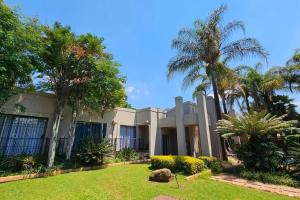 a large house with palm trees and a yard at Grobler's Haven in Pretoria
