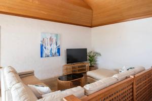 a living room with couches and a flat screen tv at Sandilands One - Oceanstays in Yamba +24 photos