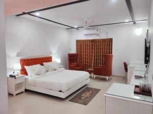 a bedroom with a white bed and a red chair at Hotel Hindustan Inn in Kuchaiburi