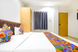 FabHotel Aashiyana في إندوري: غرفة نوم مع سرير أبيض كبير مع وسائد ملونة