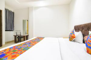FabHotel Aashiyana في إندوري: غرفة نوم مع سرير أبيض مع بطانية ملونة
