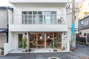 ein weißes Haus mit Balkon darüber in der Unterkunft hotel & cafe ksnowki in Dejimamachi