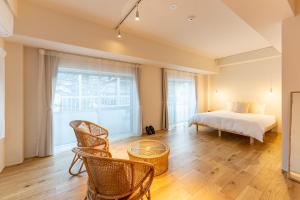 ein Schlafzimmer mit einem Bett und Stühlen sowie einem großen Fenster in der Unterkunft hotel & cafe ksnowki in Dejimamachi