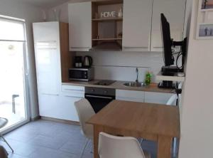 eine Küche mit weißen Schränken und einem Holztisch in der Unterkunft Apartments J&M 2 in Podglavica