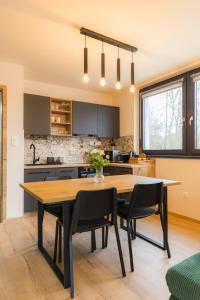cocina con mesa de madera y sillas negras en Szemespart Residence Apartmanok By BLTN, en Balatonszemes
