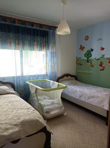 een slaapkamer met 2 bedden en een babybedje bij AMEL Familiar HOUSE in Durrës