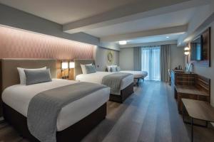 a hotel room with two beds and a desk at Riu Plaza The Gresham Dublin in Dublin